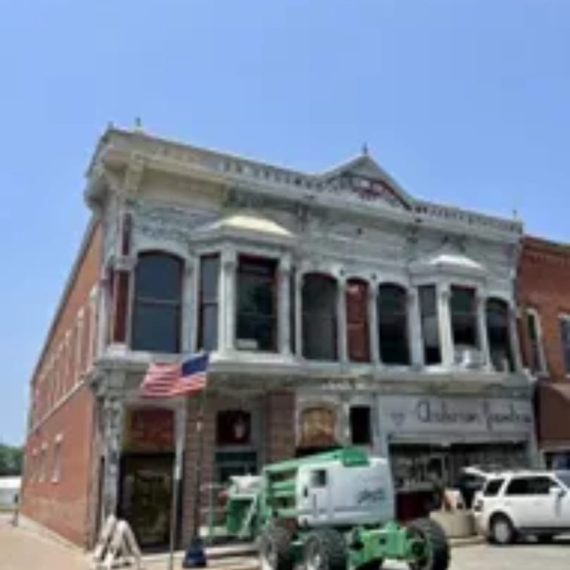 A historic brick building with ornate white trim, an American flag, and a green construction lift.