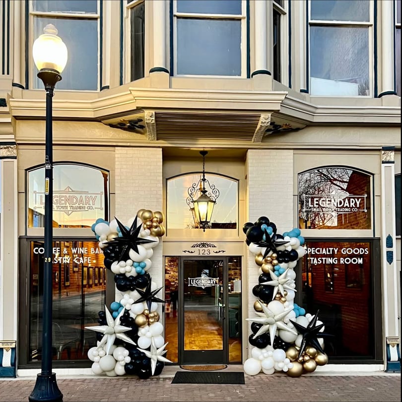 The storefront of Legendary Small Town Trading Co. with balloon arches and a street lamp.